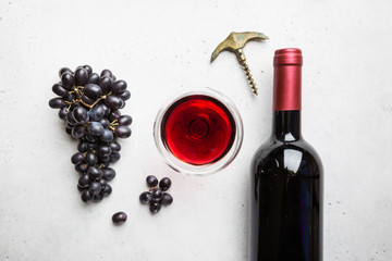 Red wine in a glass and ripe grapes on white background, top view