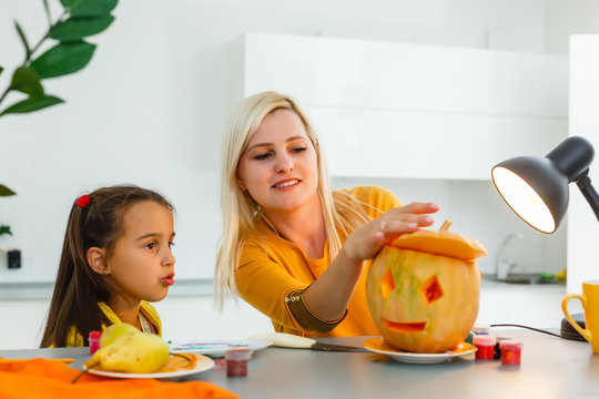 Mother and daughter carving pumpkin in the kitchen