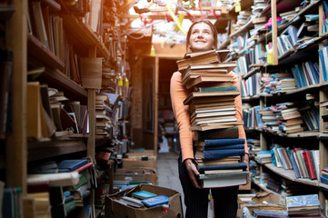 girl student carries a large stack of books in the library, preparation for study, knowledge is power, concept © Богдан Маліцький