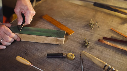 Shoemaker sharpens knife. Working process of handmade leather production in tanner workshop.