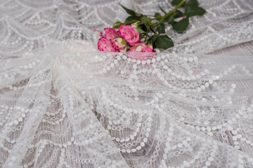 White wooden background with white spring flowers roses and lace ribbon. Happy womans day. The texture of lace on wooden background.