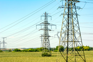 High voltage electricity pylons and transmission power lines on the blue sky background.