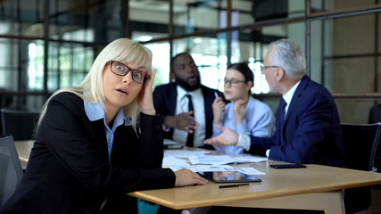 Overworked business lady tired of stressful job, colleagues arguing background