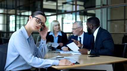 Irritated company worker feeling headache, rubbing temples, colleagues arguing