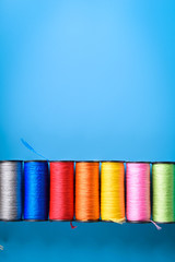  Colored thread coils on blue background, sewing, place for text