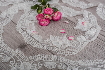 White wooden background with white spring flowers roses and lace ribbon. Happy womans day. The texture of lace on wooden background.