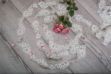 White wooden background with white spring flowers roses and lace ribbon. Happy womans day. The texture of lace on wooden background.