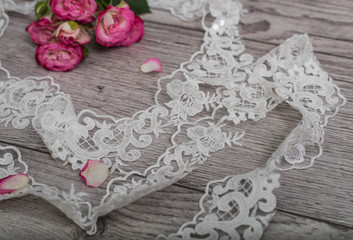 Obraz na płótnie Canvas White wooden background with white spring flowers roses and lace ribbon. Happy womans day. The texture of lace on wooden background.