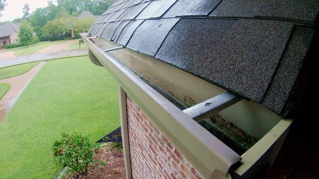 Boom up shot of gutter on brick home during rain storm