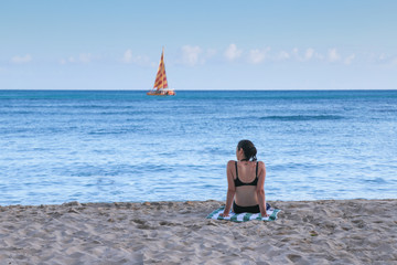 young woman on the beach seeing boat in distance