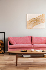 Comfortable velvet pastel pink couch in elegant beige interior with abstract painting