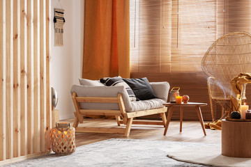 Orange candle on wooden coffee table in cozy living room interior