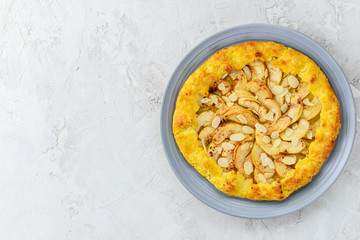 Cottage cheese galette with apples, cinnamon and almonds on a gray background.