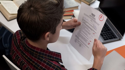 Fototapeta na wymiar Child reading test result holding paper sheet with negative mark, school system