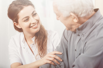 Obraz na płótnie Canvas Beautiful volunteer smiling at senior man at nursing home