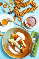 Pancakes, a traditional dish of Russian national cuisine with honey, tea, nuts and dried fruits on a blue background. Top view.