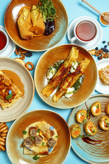 Pancakes, a traditional dish of Russian national cuisine on a blue background. Traditional treat for the holiday Maslenitsa. Top view. Restaurant table setting