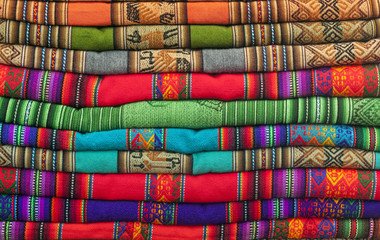 A pile of colorful Andean textiles photographed in the local handicraft market of Cusco