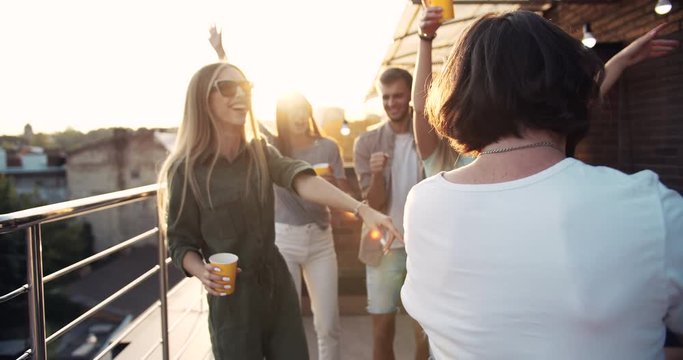 Happy bearded hippie male joining cheerful friends on roof terrace party, chillout