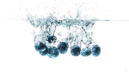 Fresh blueberries falling in water on white background. Fruits splashing into clear water.