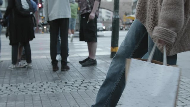 Super slow motion shot of a young woman swinging colorful shopping bags in the city.