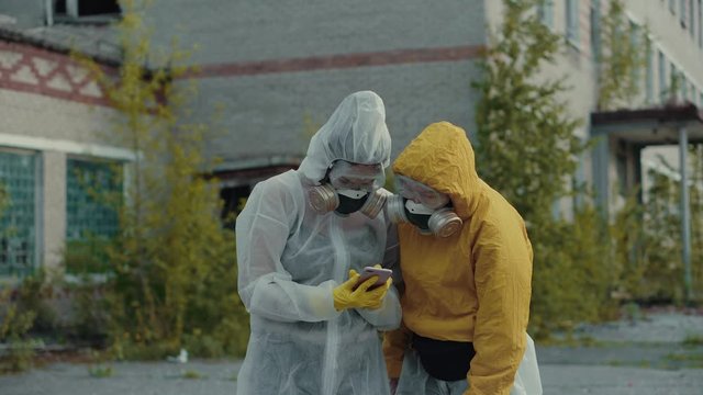 Scientists put on respirators and take pictures on the phone. Girls in a protective suit from radiation take selfies. Ecological theme. Terrible abandoned territory in Novosibirsk.