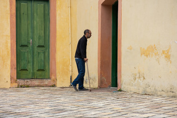 Elderly man with leg problem walks with cane