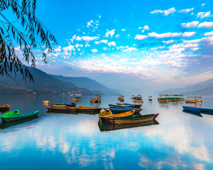 Sunrise in Phewa Lake with Multicolor boats.blue sky reflection in the lake.