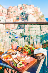 Tasty italian snack. Fresh bruschettes, cheeses and meat on the board in cafe with view in Manarola