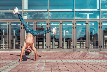 fitness in jump, handstand, sport man dancing break dance, naked torso inflated, young guy, free space text lifestyle motivation, summer in city background glass building window in motion