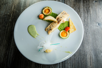 baked white fish piece decorated with avocado and puree