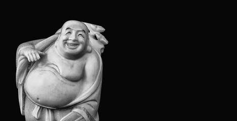 Budai, the "Laughing Buddha" figurine on black background (Black and White with copy space)
