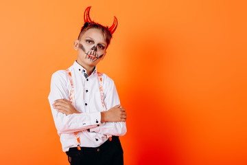 Portrait of boy in Devil masquerade makeup folded hands and looking at the camera. Halloween concept