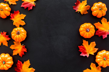 Autumn background with leaves and pumpkins on black top view copy space frame