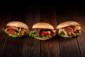 close up of three kebab sandwiches on wooden background