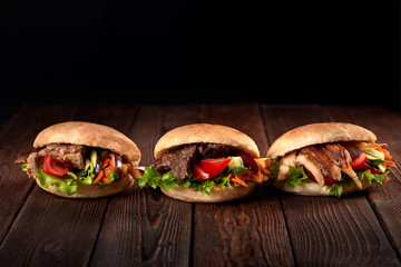 close up of three kebab sandwiches on wooden background