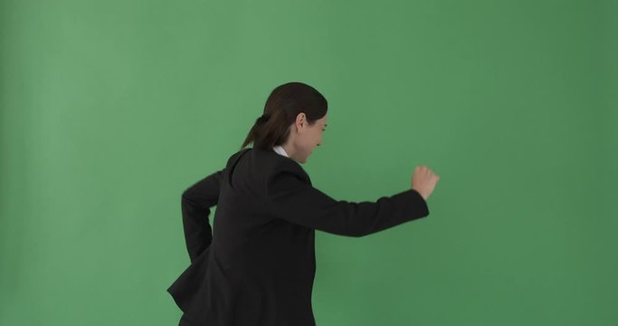 Joyful businesswoman dancing over green background