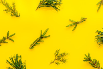 New Year background with fir branches on yellow table top view flat lay pattern