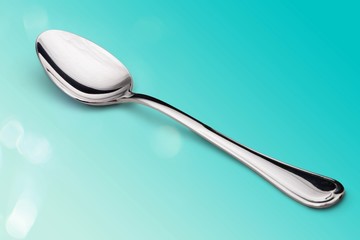 Metal spoon on blue background close-up