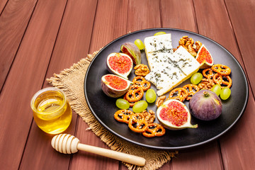 Cheese plate with blue cheese, honey, walnuts, figs, grapes, pretzels