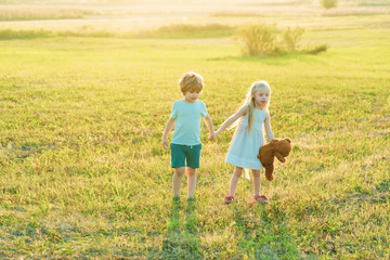 Happy children girl and boy running on meadow in summer in nature. Eco farm. Two little children on countryside farm. Happy childhood. Eco resort activities.