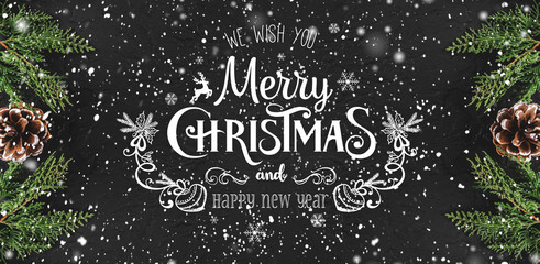 Christmas and New Year Typographical on dark holiday background with frame of Fir branches, pine cones, snowflakes. Xmas and Happy New Year theme, snow. Flat lay, top view