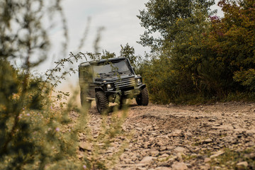 Off-road travel on mountain road. Travel concept with big 4x4 car. Motion the wheels tires and off-road that goes in the dust on the sand. Best Off Road Vehicles. © Volodymyr