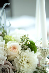 Wedding table setting is decorated with fresh flowers and white candles. Wedding floristry. Bouquet with roses, hydrangea and eustoma. Table numbering