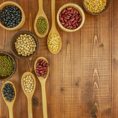 Flat lay,top view assorted beans including red bean,soybeans,black beans,mung beans on brown,beige wooden background with copy space