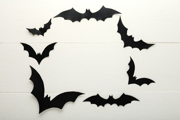 Halloween background with paper bats on white wooden background. Frame. Halloween holiday decorations. Flat lay, top view, copy space. Party invitation mockup, celebration.