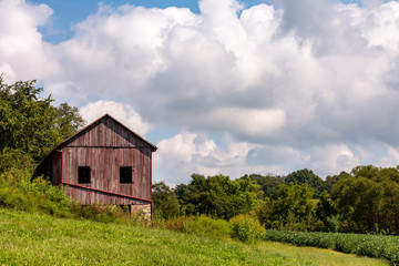 Obraz premium landscape of a red barn on a hillside on a cloudy summer day