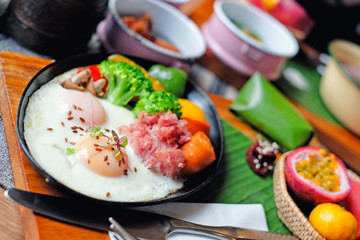 Breakfast - Fried eggs with sausages, fermented pork and vegetable served with fruits