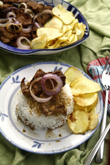 Bistek Tagalog or fried pork tenderloin in soy sauce with potato chips