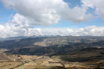 Colombian mountains landscape with andean Mountain Rage, farms and crops. Blue sky with clouds. 